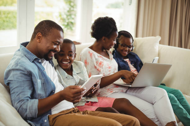 istock Parents and kids using laptop and digital tablet on sofa 646918838