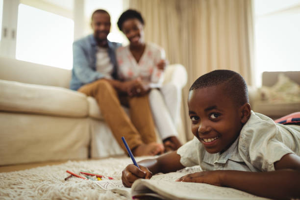 istock Portrait of boy writing in a book while lying on a rug 646922760