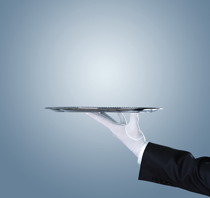 Waiter holding empty silver tray over blue background with copy space