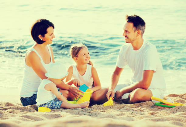 istock Parents with two kids playing with toys on beach 646926490