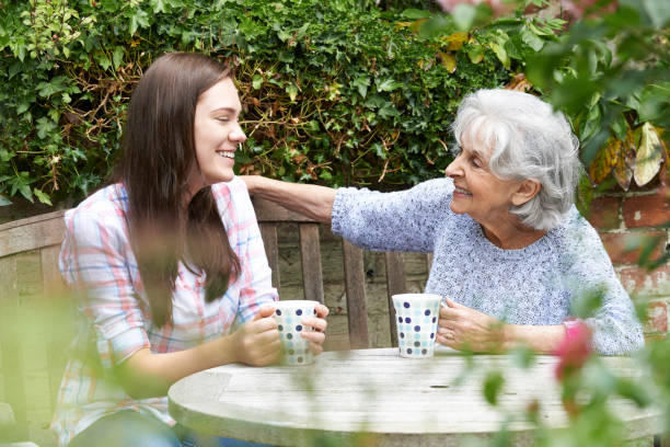 Teenage Granddaughter Relaxing With Grandmother In Garden Teenage Granddaughter Relaxing With Grandmother In Garden friends drinking tea stock pictures, royalty-free photos & images