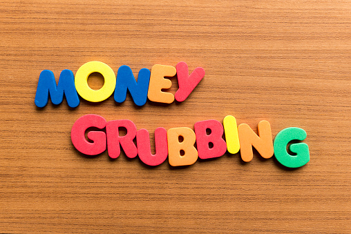 money grubbing colorful word on the wooden background