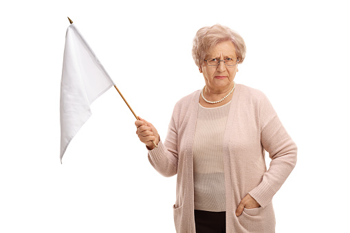 Disappointed mature woman holding a white flag isolated on white background
