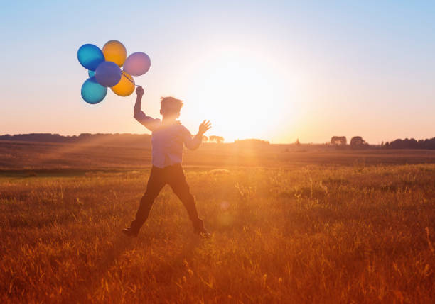 istock boy with balloons at sunset 646946744