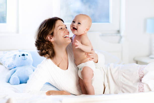 baby and mother at home in bed. mom and child. - mother baby new kissing imagens e fotografias de stock