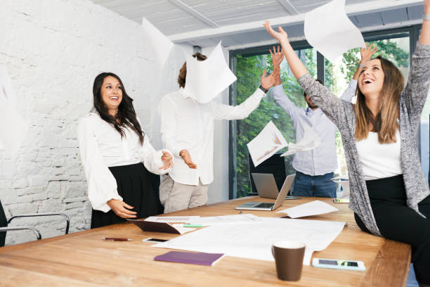istock Young business group at meeting table in office tosses the sheets for happiness 646960032