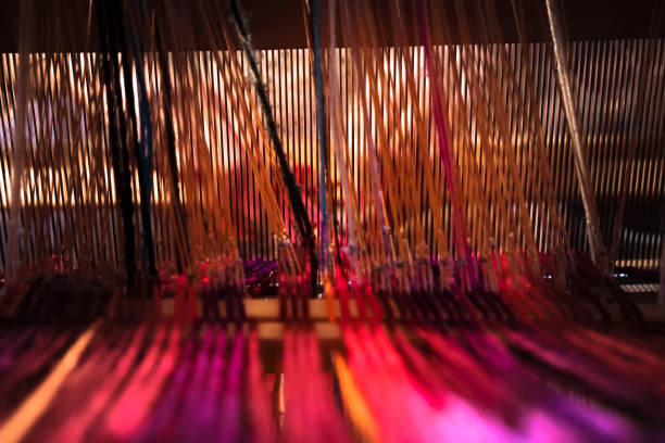 Woman hands introducing colorful yarn thread in to the loom. Focus on threads in foreground, hands in background. Handloom Weaver making woman's hat from weaving to final product series of photos.