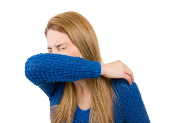 Woman Sneezing Into Arm stock photo