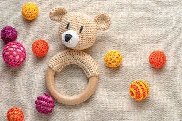 amigurumi toy bear and crocheted beads on a knitted background with copy space