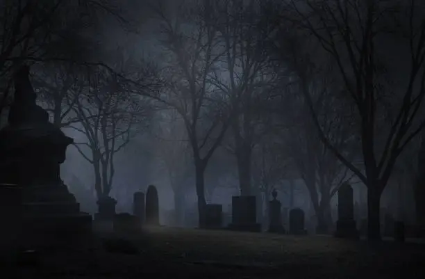 Spooky cemetery at night with fog. Desaturated color.