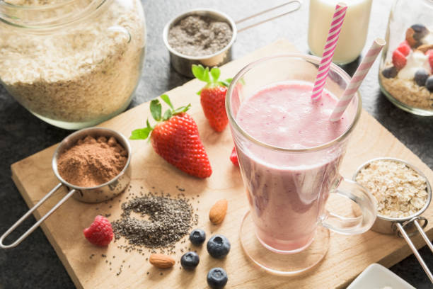 istock Fresh pink fruit smoothie surrounded by ingredients on wooden board 647001650