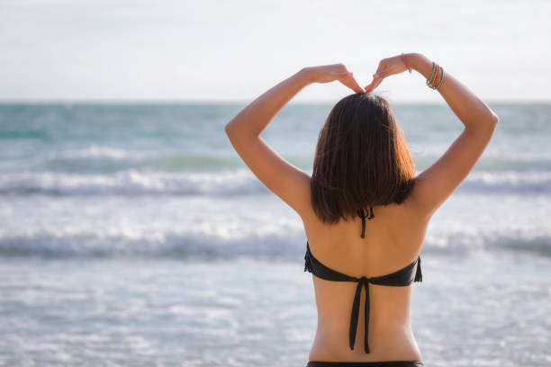 istock Woman with black bikini making heart sign on beach 647018752