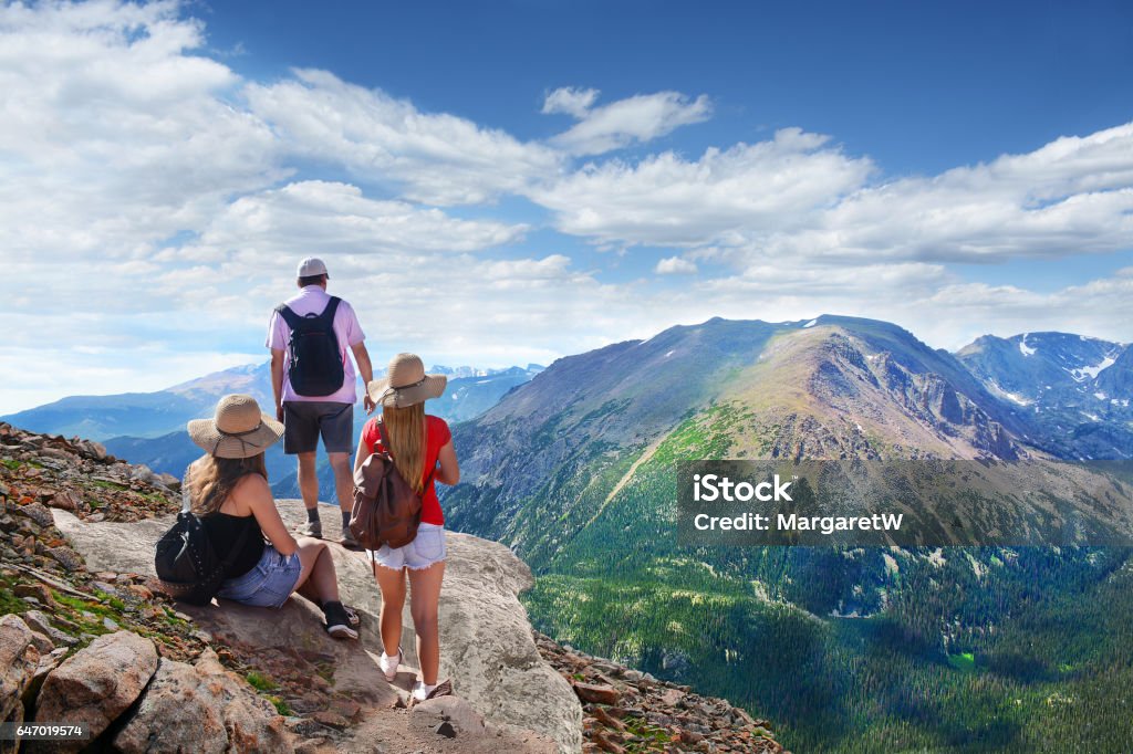 Family relaxing on top of the beautiful mountain. People standing on top of mountain rock. Family looking at beautiful summer landscape from Trail Ridge Road on vacation  hiking trip. Rocky Mountain National Park landscape. Colorado, USA. Colorado Stock Photo