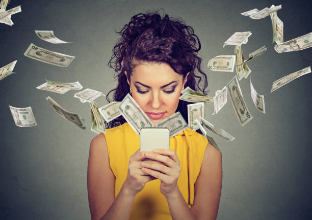 istock woman using smartphone with dollar bills flying away 647025532
