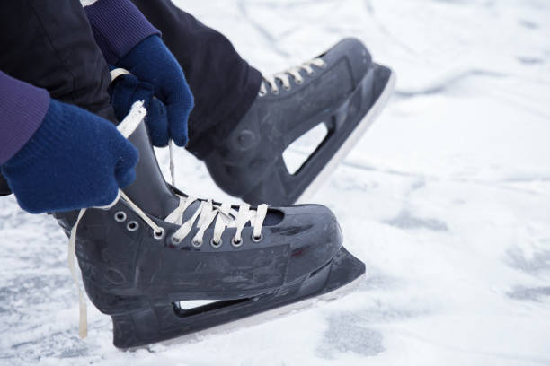 istock Man tying his black skates on the ice area. Winter. 647025610