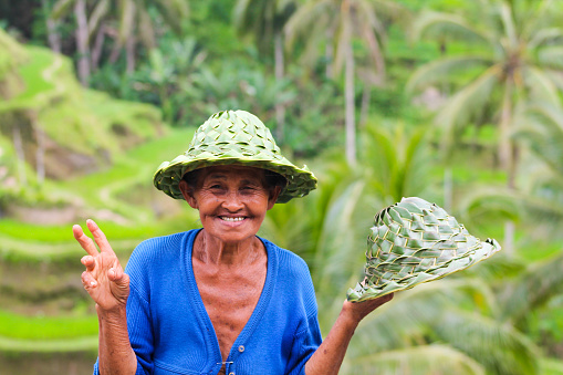 BALI, INDONESIA - September 9, 2013  : happy local woman sell hats in bamboo near rice terraces
