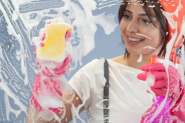 istock Young woman washing window 647030710
