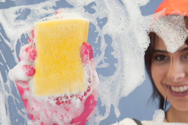 istock Young woman washing window 647033118