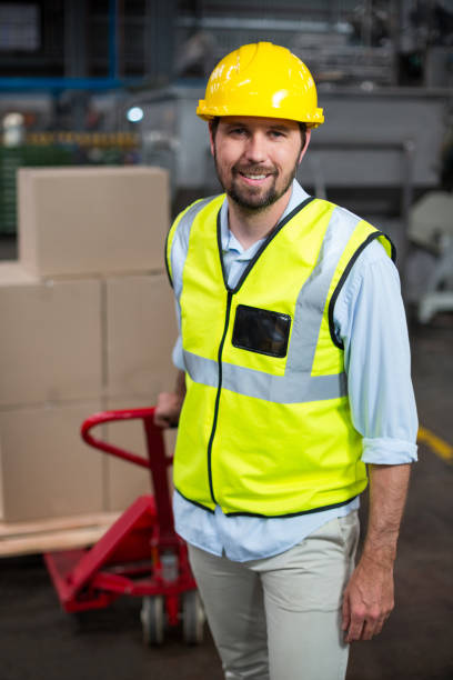 istock Factory worker pulling trolley of cardboard boxes in factory 647050490