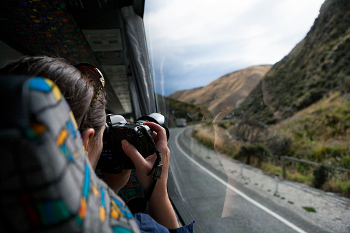 Tourist aboard bus photographing the country of New Zealand