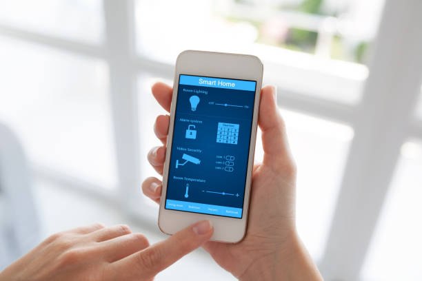 istock female hands holding white phone smart home screen against window 647060246