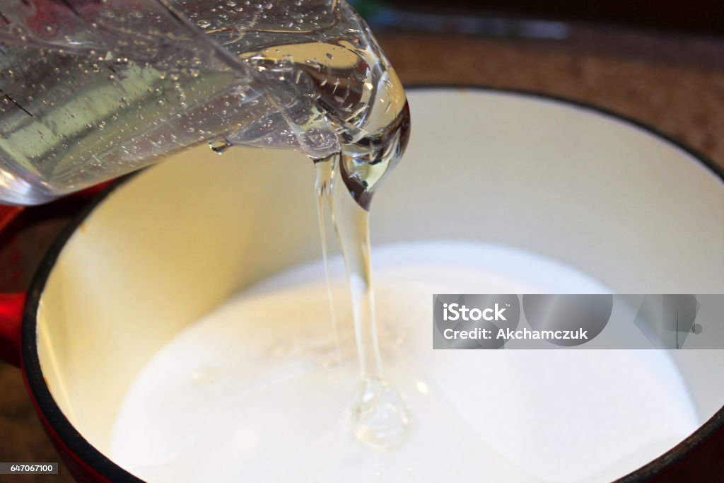 Verser le sirop de maïs dans une casserole pour faire des bonbons durs - Photo de Sirop libre de droits