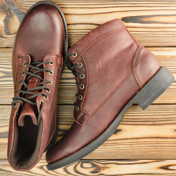 istock Stylish brown leather boots for men on wooden background, top view. 647083748