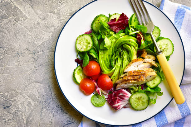 Fresh green salad with grilled chicken Fresh green salad with grilled chicken in a plate on a grey slate,stone or concrete background.Top view with copy space. paleo diet stock pictures, royalty-free photos & images