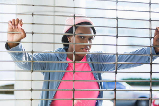 istock Young black woman looking through metal grate 647090320