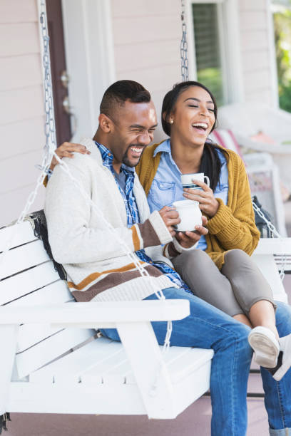 istock Young mixed race couple drinking coffee on porch swing 647095930