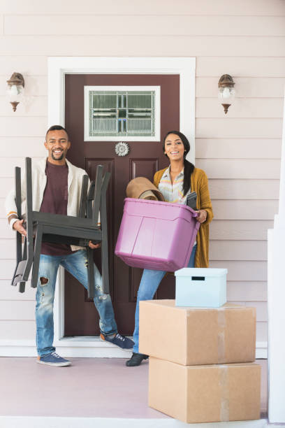 istock Young couple moving, carrying belongings thru front door 647096172