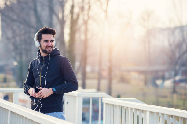 istock Man jogger with smartphone and headphones in sunset 647096746