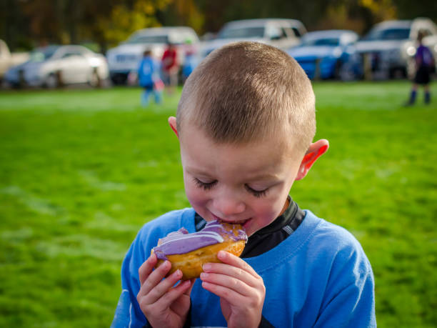 istock Young boy with long eyelashes eating a donut 647099078
