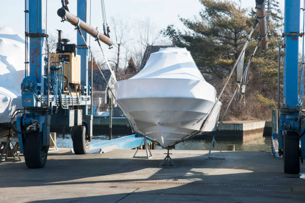 A boat is carefully lifted under a covered structure for essential maintenance, showcasing preparations and tools
