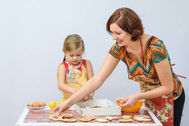 istock Five-year girl with her mother put in a box shaped painted gingerbread 647116526