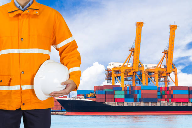 istock Engineer dockers holding helmet in front of an industrial harbor 647124000