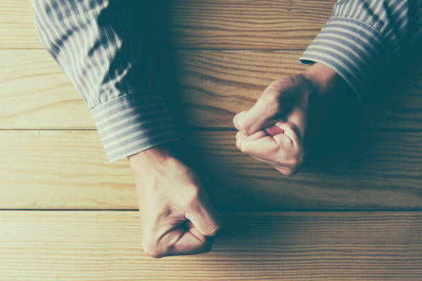 istock man fists clenched on a wooden table in anger 647129600