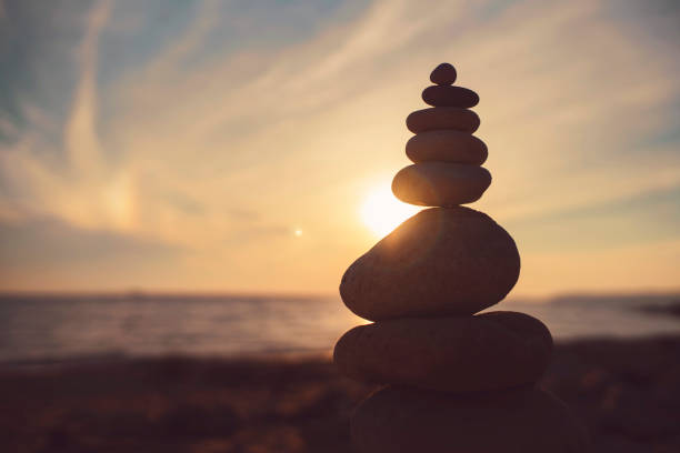 Stone Sculpture Sculpture of piled-up stones on the beach and the sunset behind. stackable stock pictures, royalty-free photos & images
