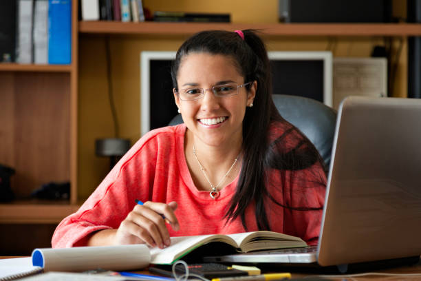 istock Pretty smiling hispanic young woman working and writing using laptop 647137526