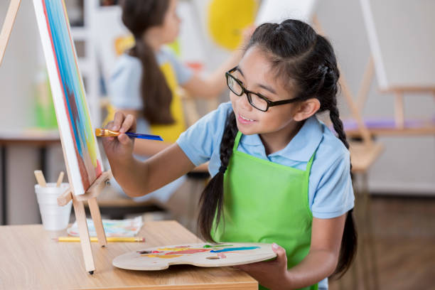 istock Cheerful girl paints in art class 647137972