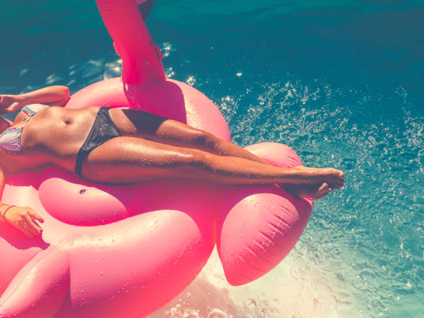 istock Woman floating on a pink inflatable in swimming pool 647142470