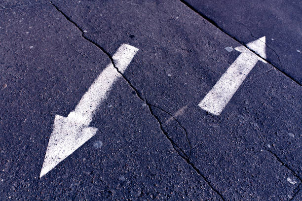istock Two arrows on blue toned cracked asphalt surface 647167350