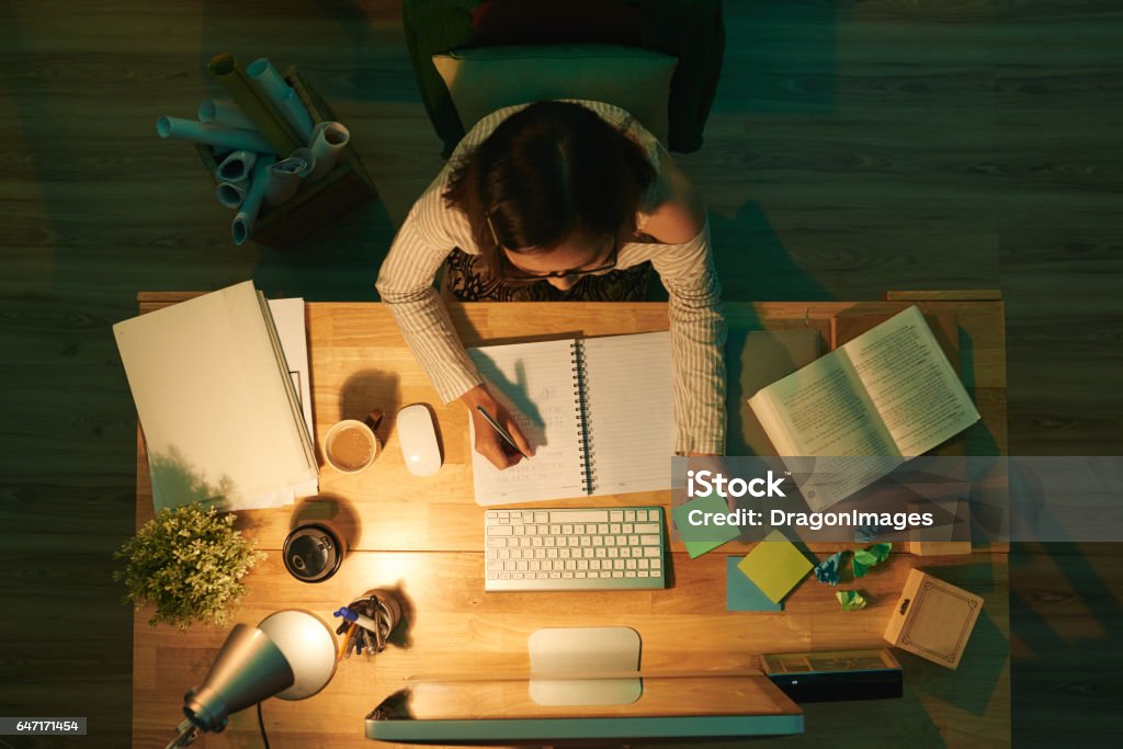 Studying at night Female student doing homework, view from above Studying Stock Photo