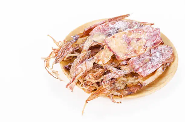 Dried squids in wooden dish isolated on white background.