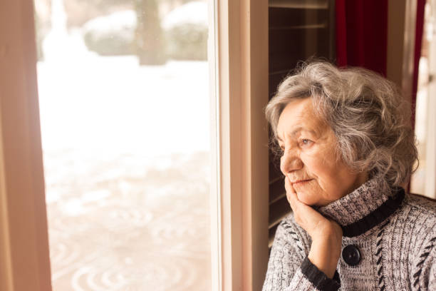 istock Senior woman looking through window 647175712