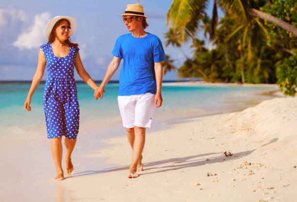 istock happy loving couple walking on summer beach 647187406