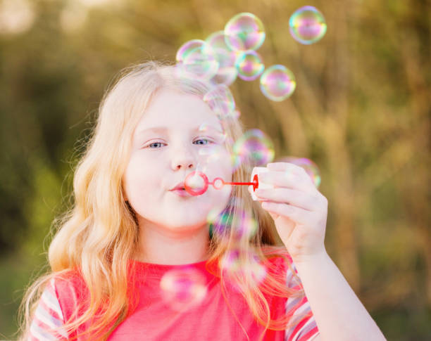 istock girl blowing soap bubbles outdoor at sunset 647191116
