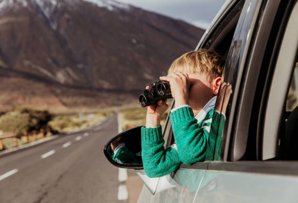 маленький мальчик, глядя через бинокль во время путешествия на машине по дороге - little boys discovery binoculars child стоковые фото и изображения