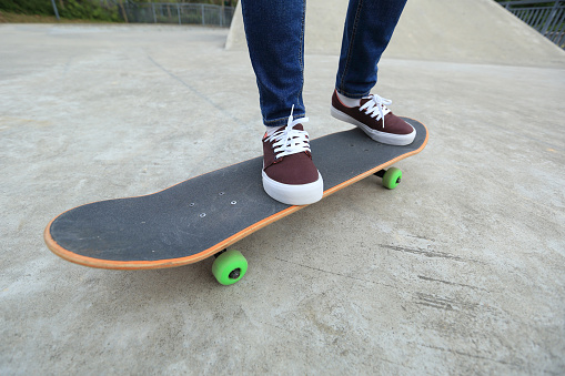 young skateboarder legs riding skateboard at skatepark