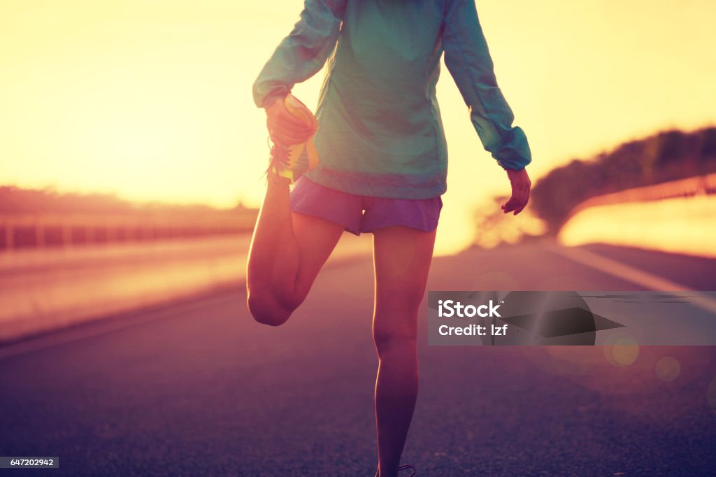 young fitness woman runner stretching legs on city road Active Lifestyle Stock Photo